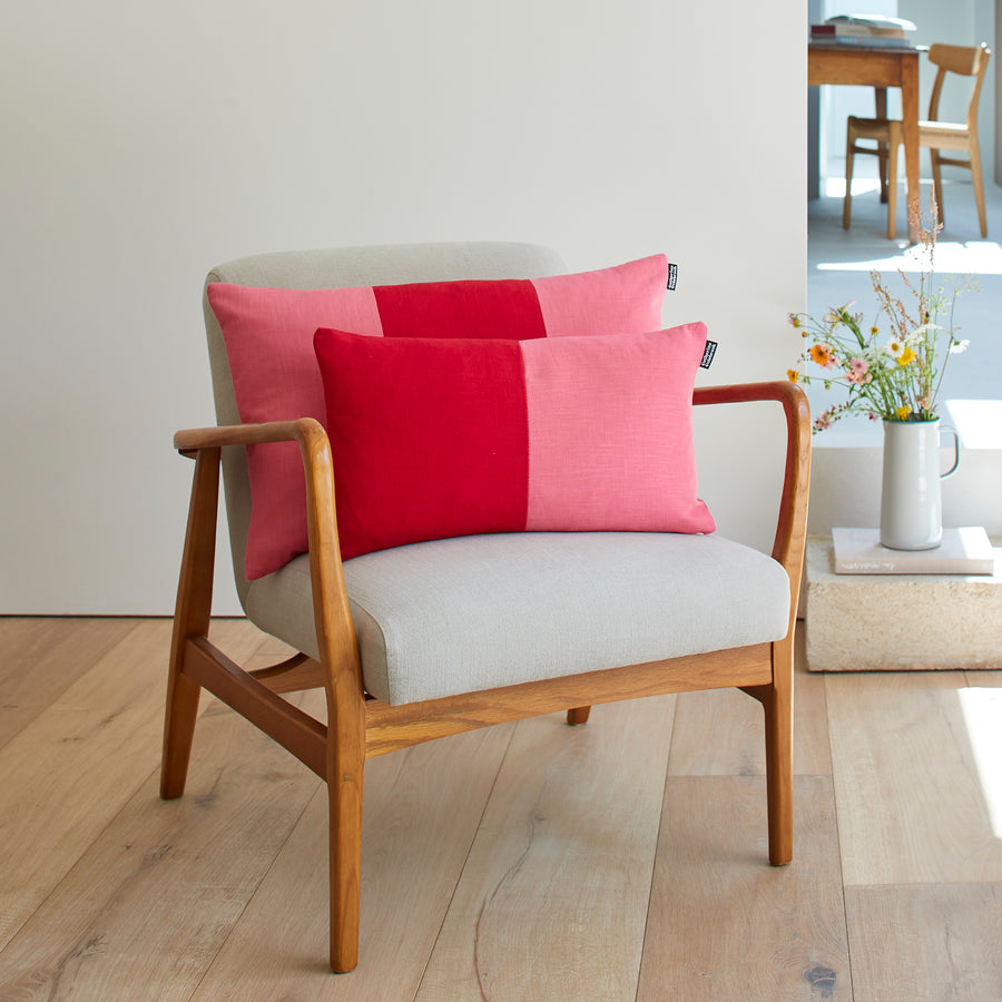 CATHERINE COLEBROOK DOUBLE COLOUR BLOCK CHERRY ROSE CUSHION ON A CHAIR