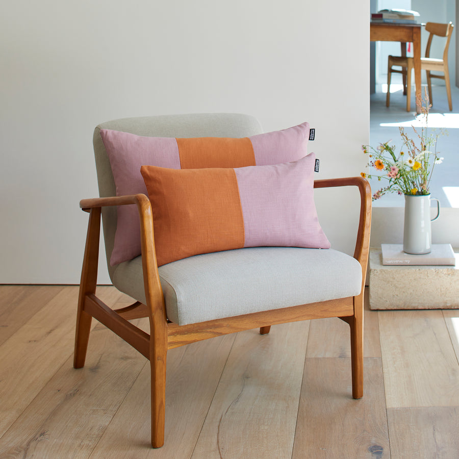 CATHERINE COLEBROOK DOUBLE COLOUR BLOCK DUSKY GINGER CUSHION ON A CHAIR