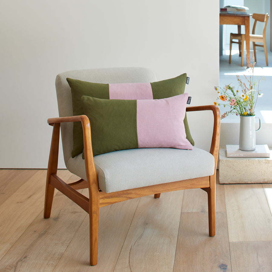 CATHERINE COLEBROOK DOUBLE COLOUR BLOCK DUSKY JUNGLE CUSHION ON A CHAIR