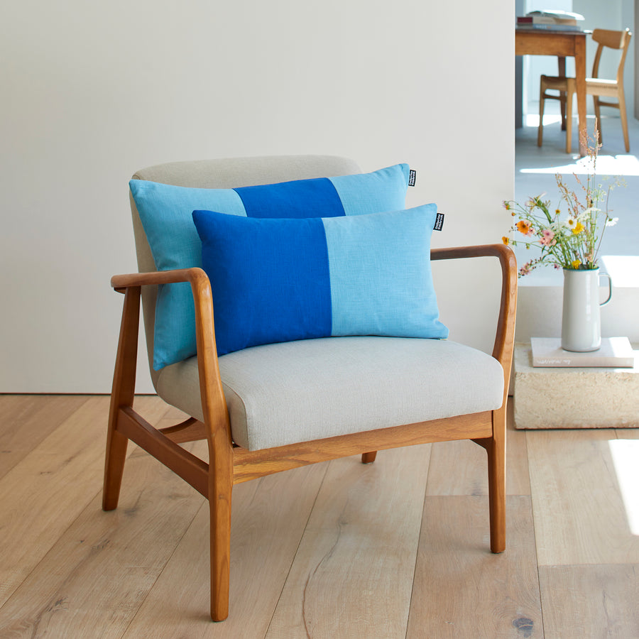 CATHERINE COLEBROOK DOUBLE COLOUR BLOCK ROYAL AZURE CUSHION ON A CHAIR