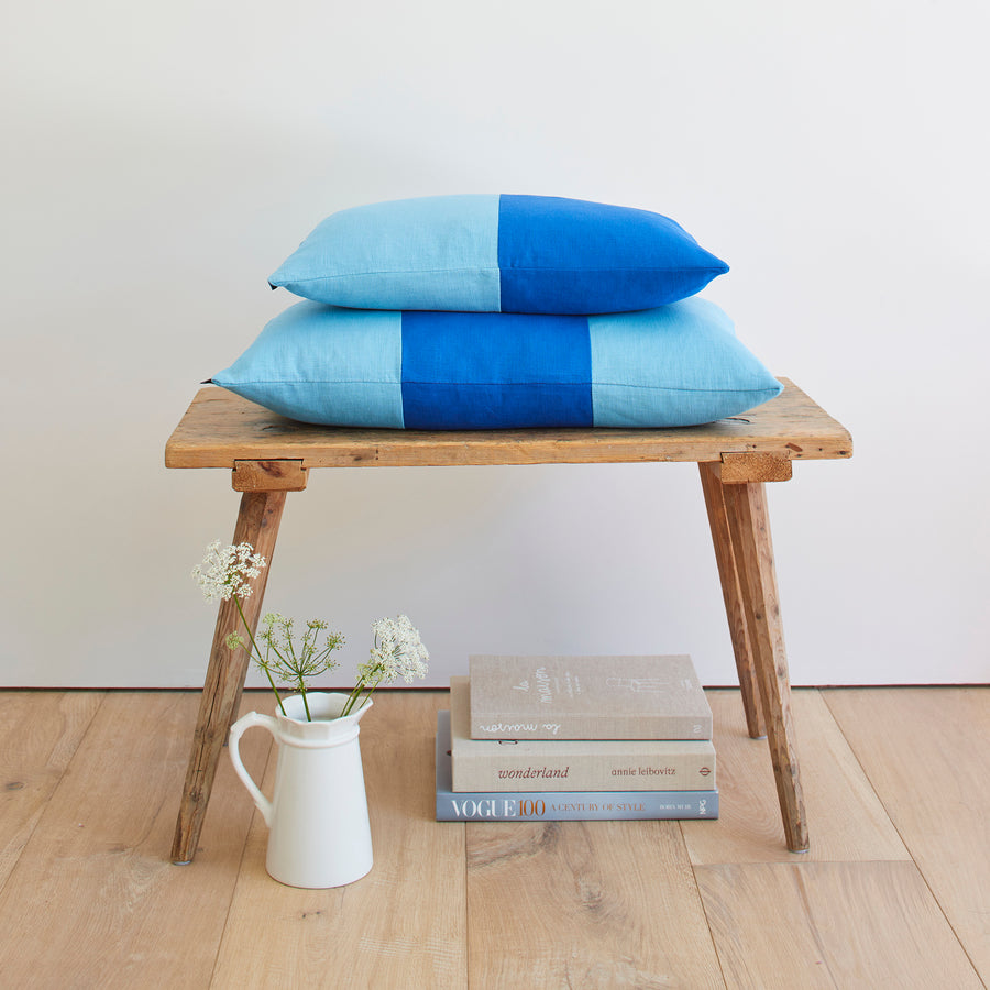 CATHERINE COLEBROOK DOUBLE COLOUR BLOCK ROYAL AZURE CUSHION ON A BENCH