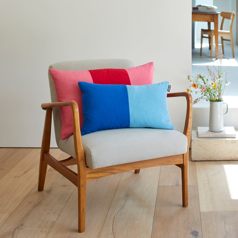 CATHERINE COLEBROOK DOUBLE COLOUR BLOCK ROYAL AZURE CUSHION ON A CHAIR WITH THE CHERRY ROSE TRIPLE COLOUR BLOCK CUSHION